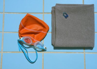 Swim cap, goggles, and towel on tiled surface.